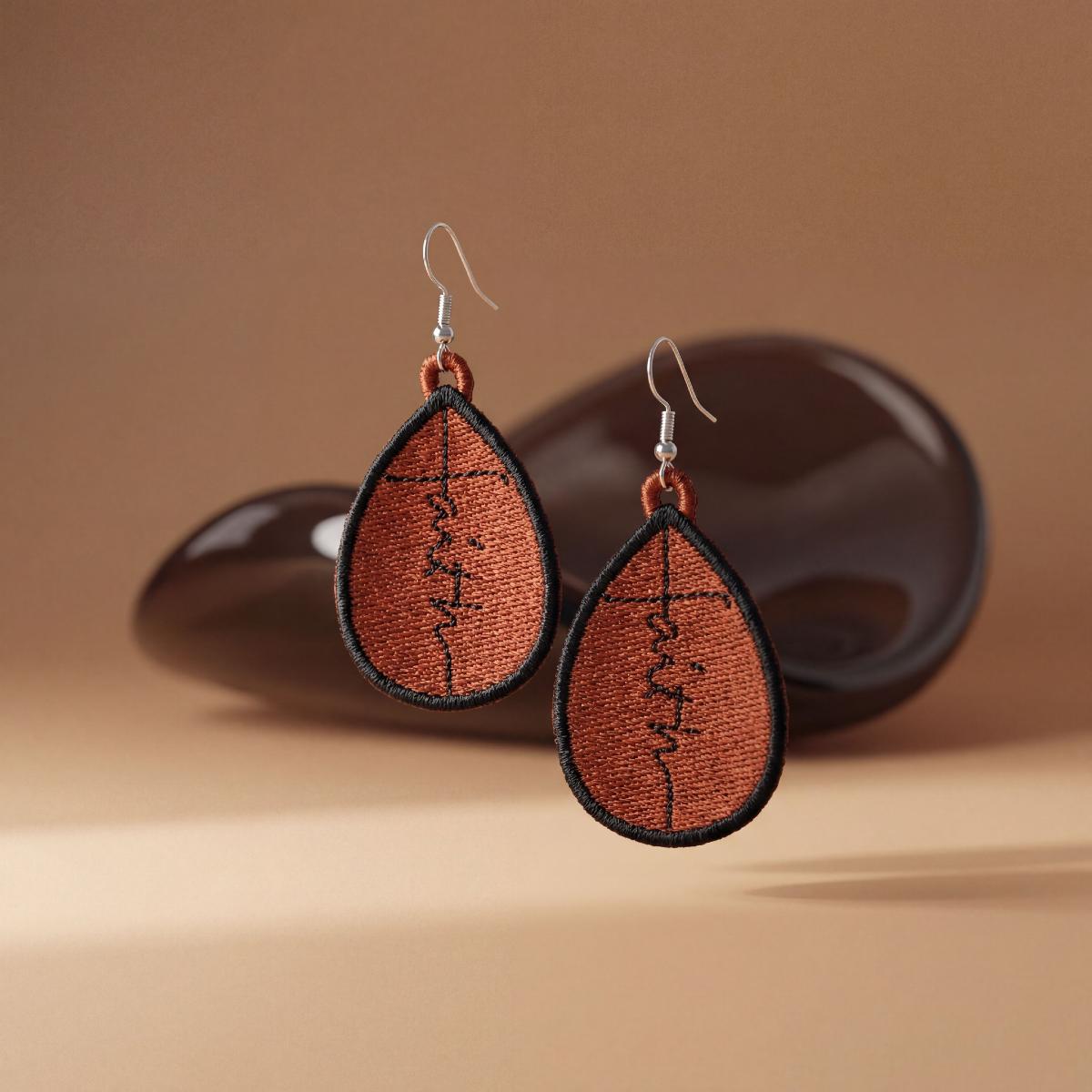 Teardrop-shaped earrings with 'faith' inscription on a brown background