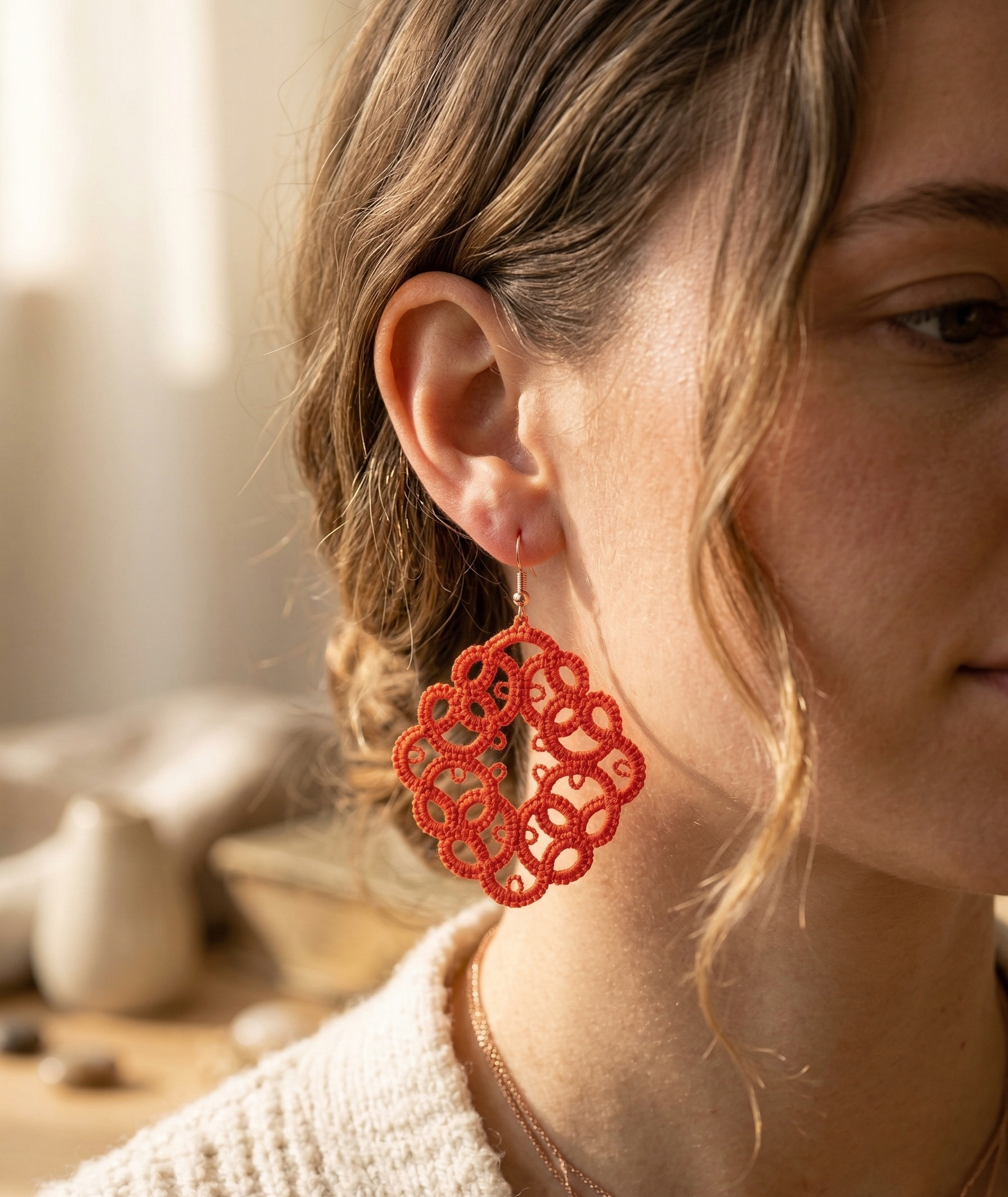 Close-up of a person wearing red earrings with a blurred background