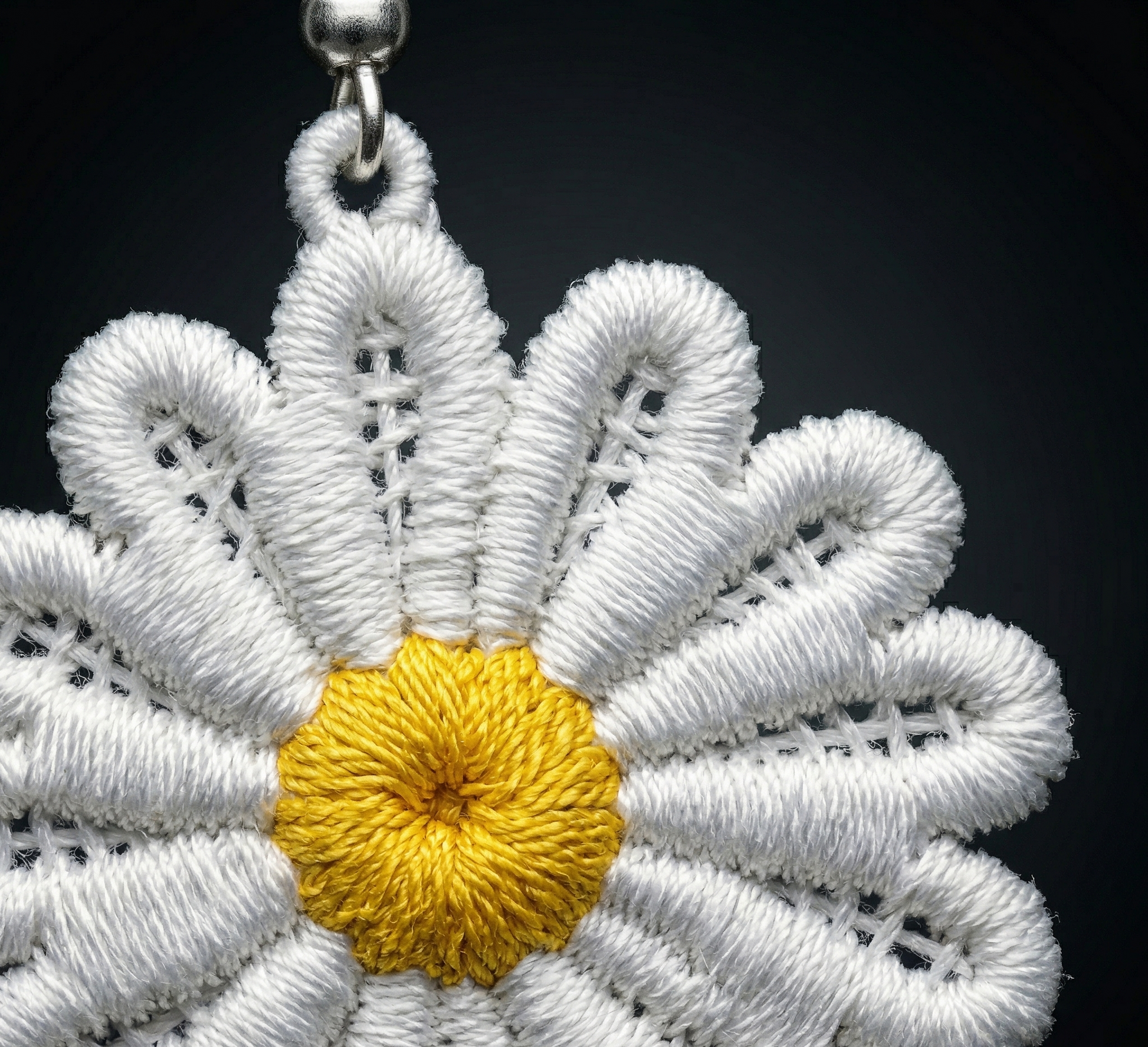 White embroidered flower with a yellow center on a black background