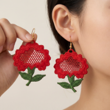 Close-up of a person wearing red floral earrings against a red background