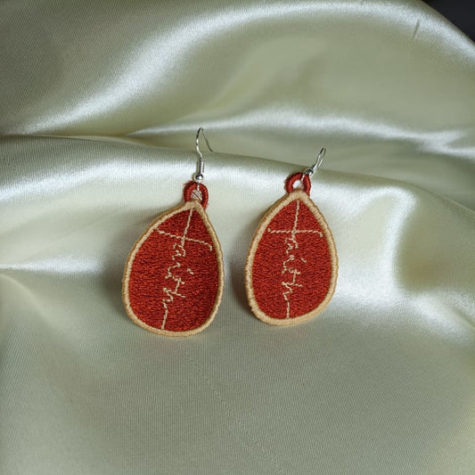 Red earrings with white designs on a satin surface