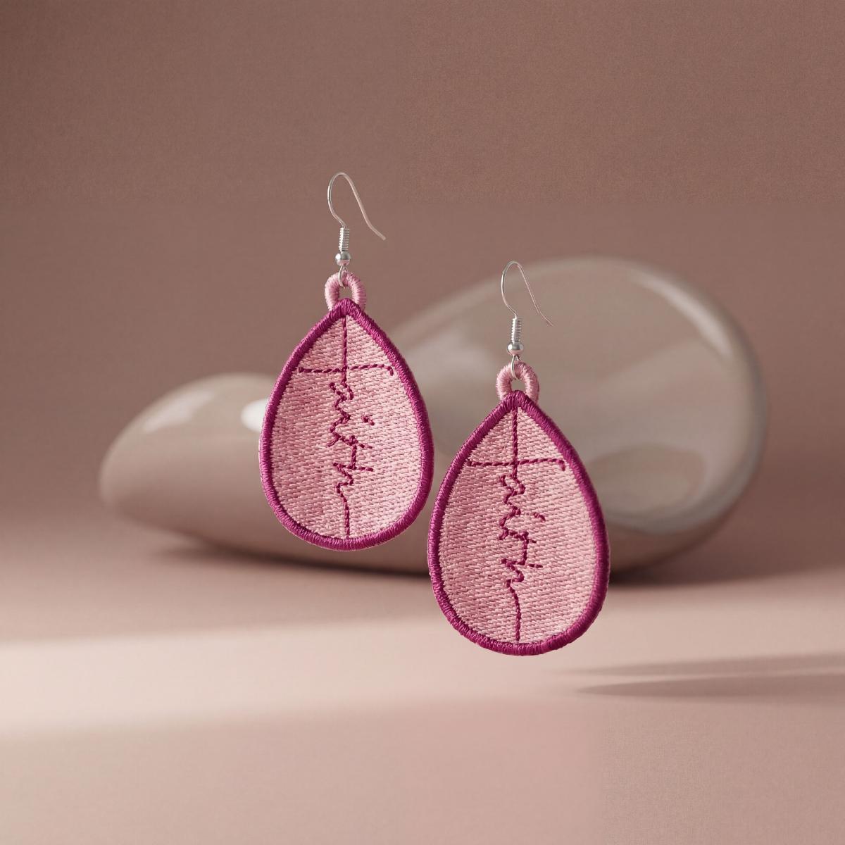 Pink embroidered earrings on a beige background