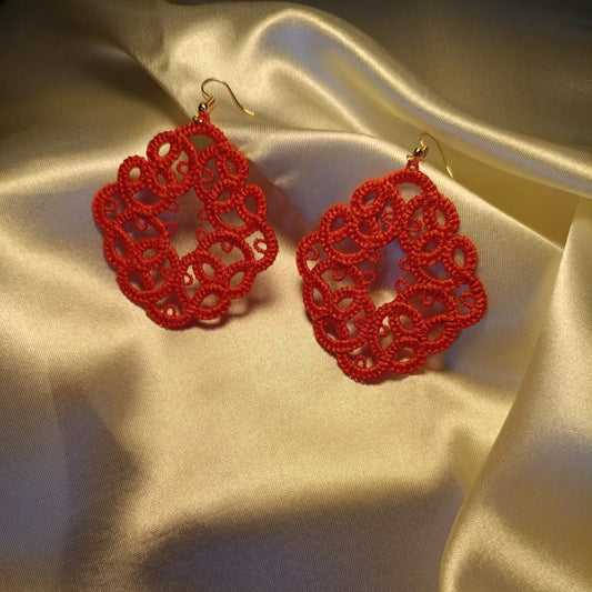 Red lace earrings on a beige fabric background