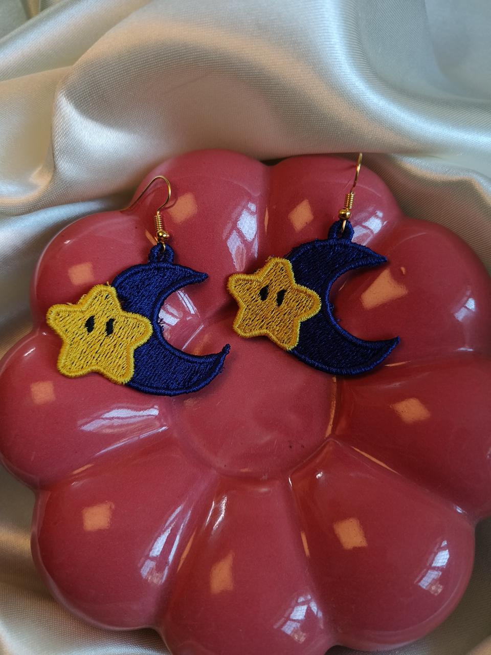 Earrings with star and moon designs on a pink flower-shaped stand.