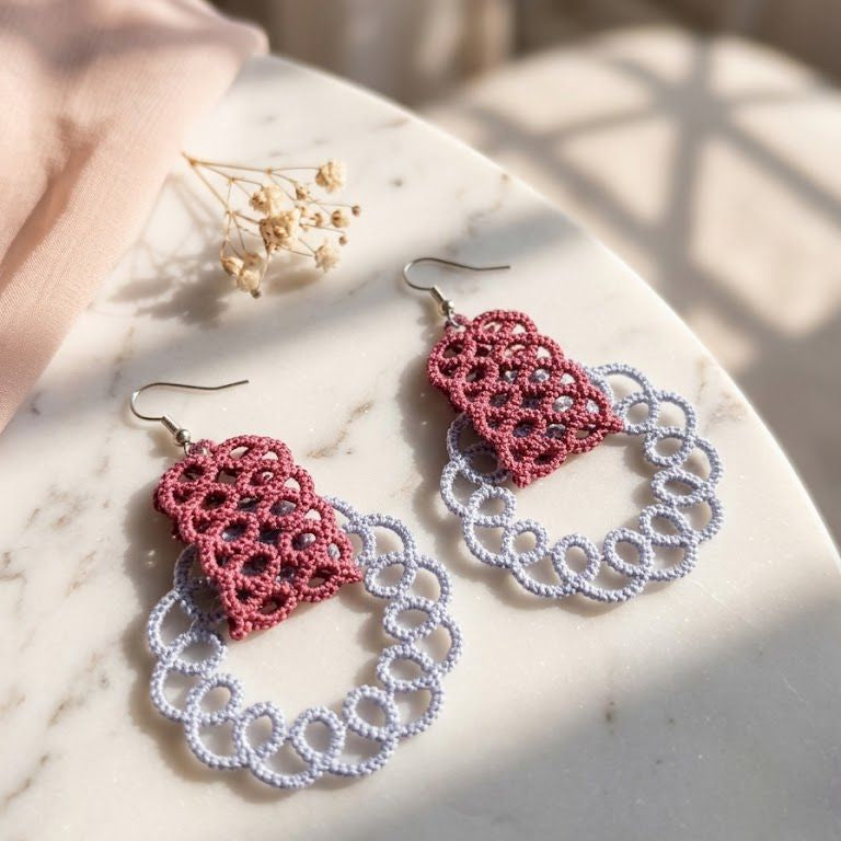 Pair of red and white lace earrings on a marble surface.