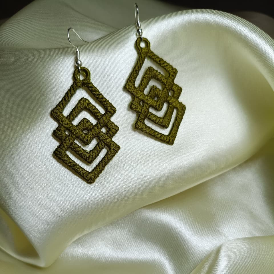 Pair of gold geometric earrings on a white satin surface