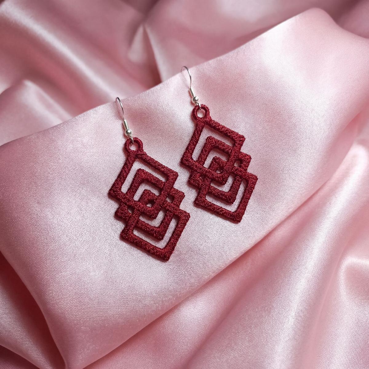 Red earrings on a pink satin background