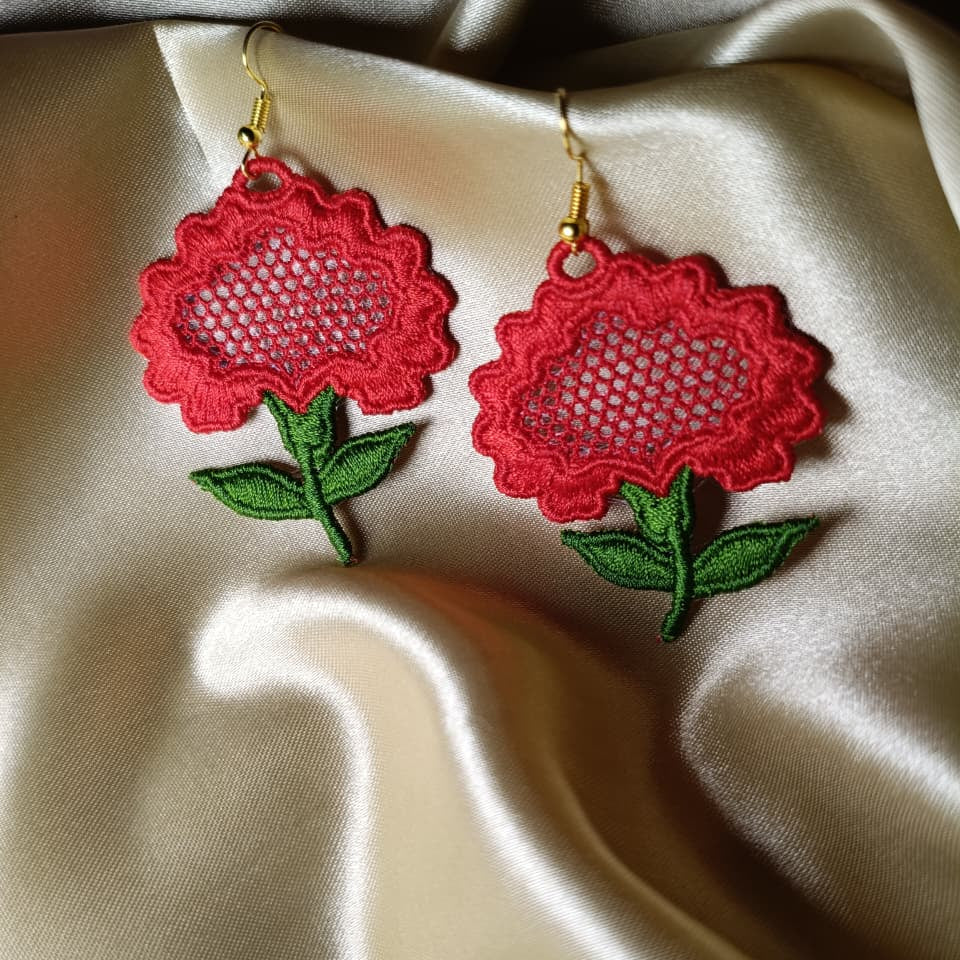 Red floral earrings on a beige fabric background