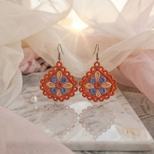 Ornate earrings on a marble surface with a soft, blurred background